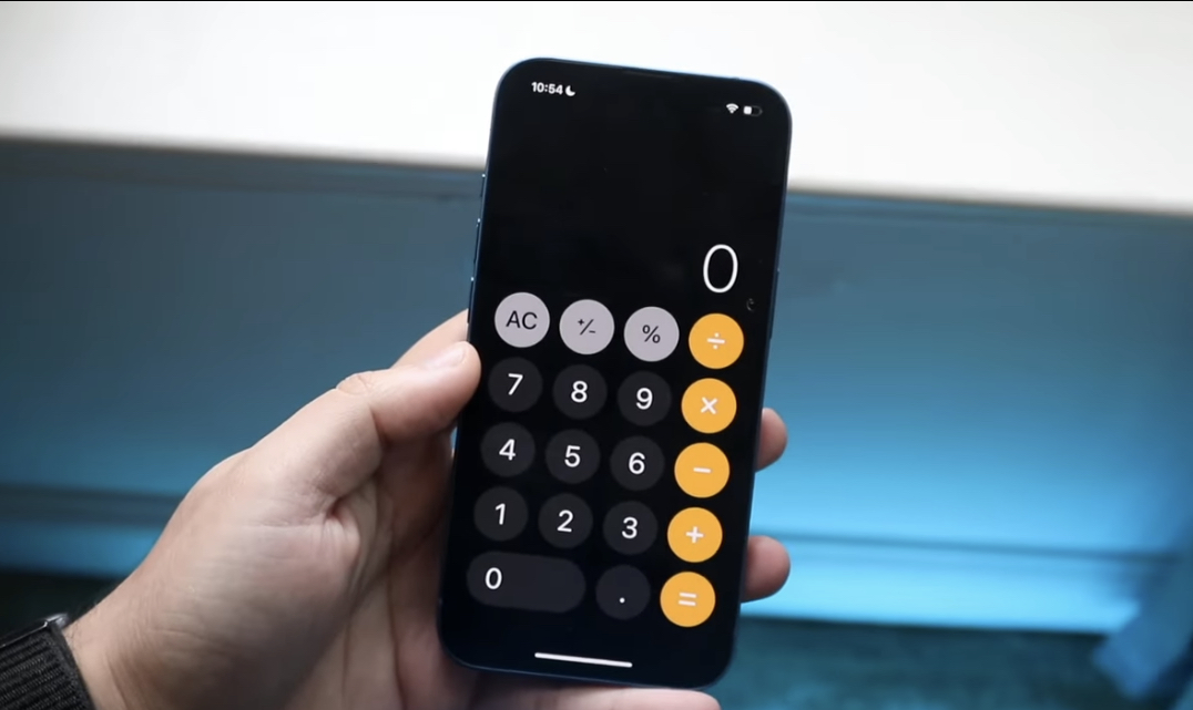 A person's hand holding a smartphone with the calculator application open